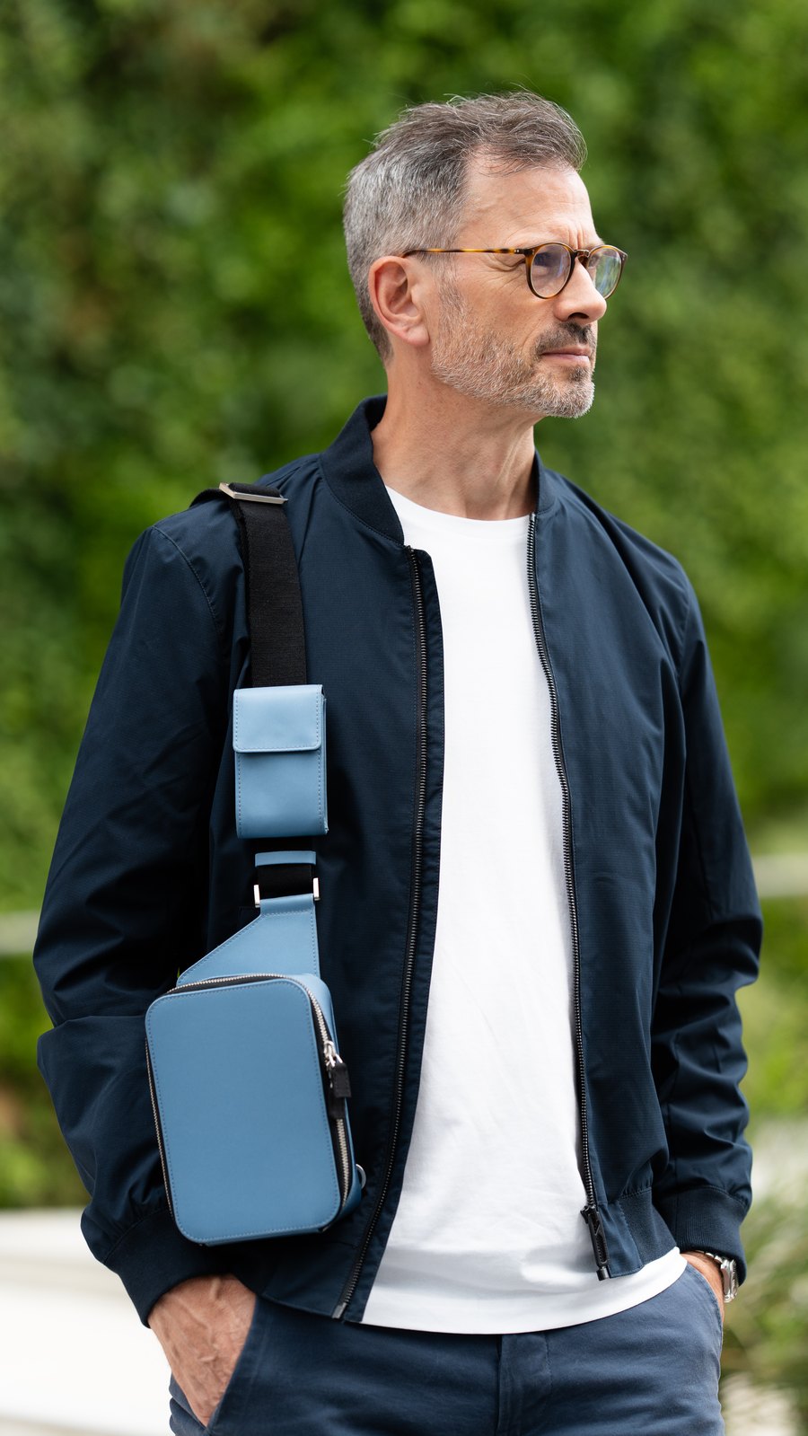 Man in a navy bomber jacket wearing The Verso in steel blue across his chest.