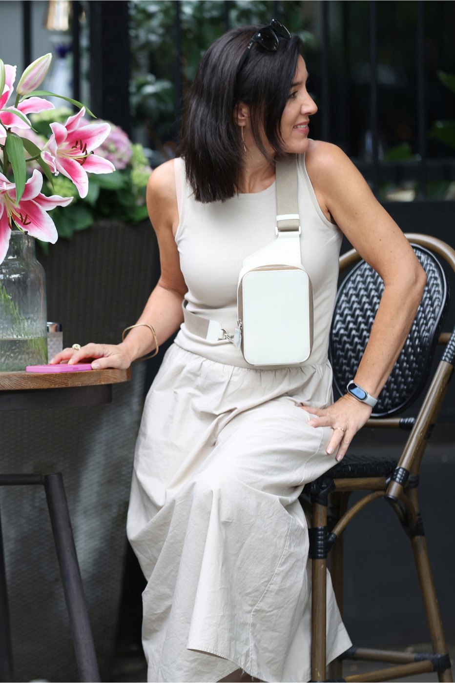 Woman at a café terrace wearing The Verso in off-white across her chest.